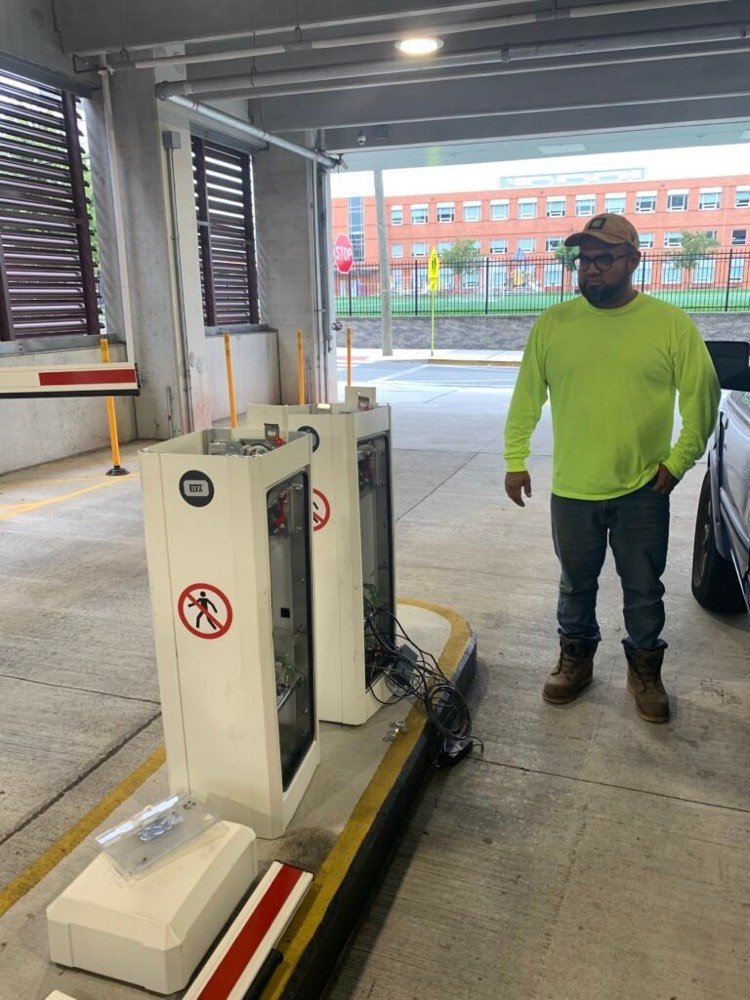 Kyosis technician beside a parking exit payment terminal in a parking garage